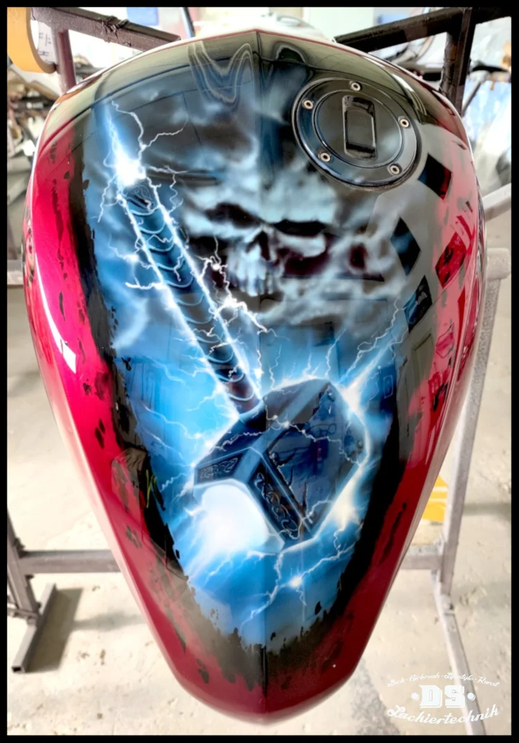 Thor-Hammer Airbrush-Design auf Motorrad-Tank mit Wolken-Totenkopf und Grunge-Effekt“